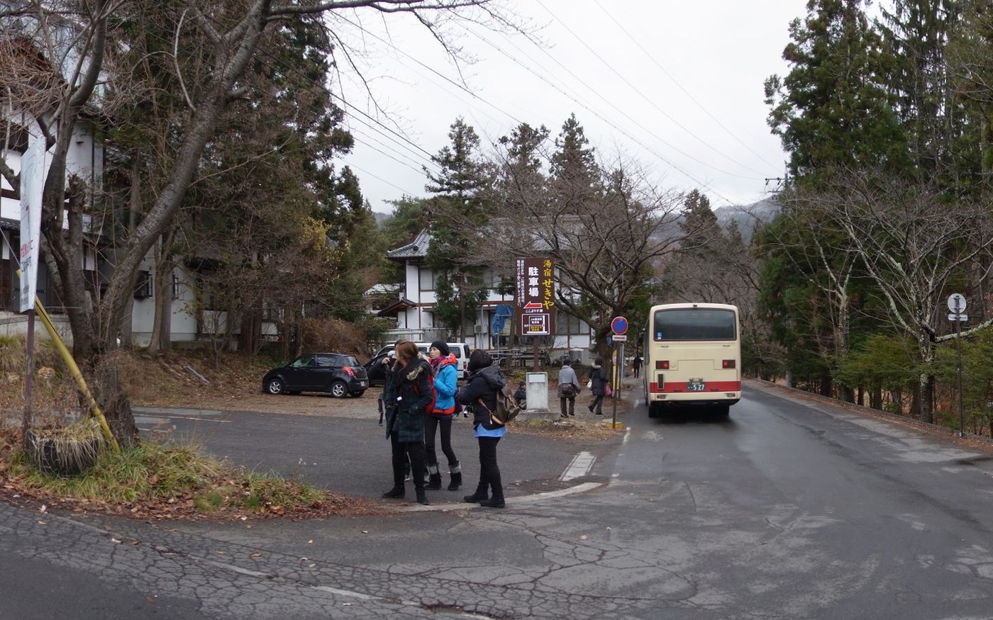 A roadside bus stop sign at Kamibayashi Onsen with a shelter and a snow-covered slope behind