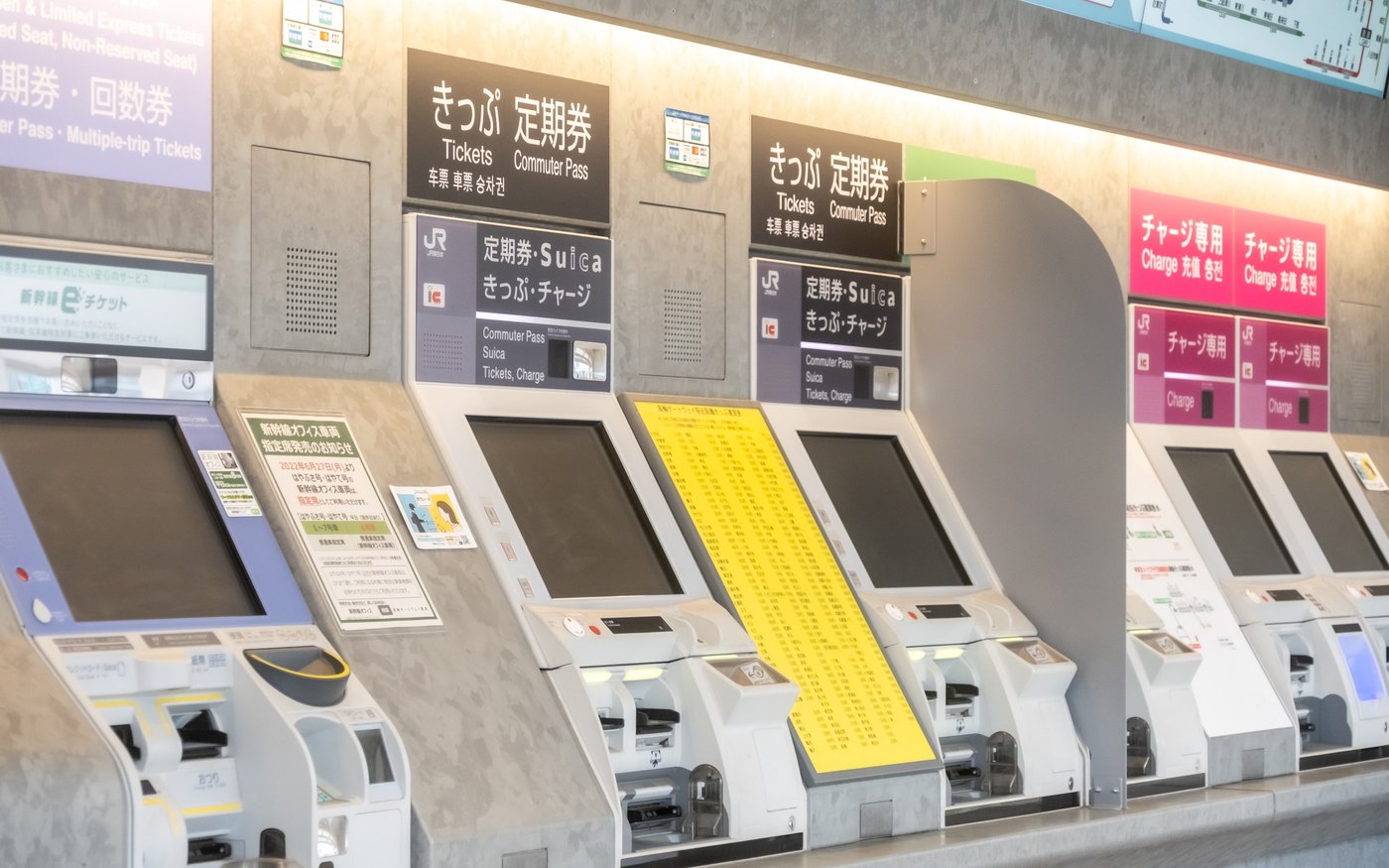 A row of JR East ticket machines, the blue panels above them reading commuter pass, Suica, tickets and charge