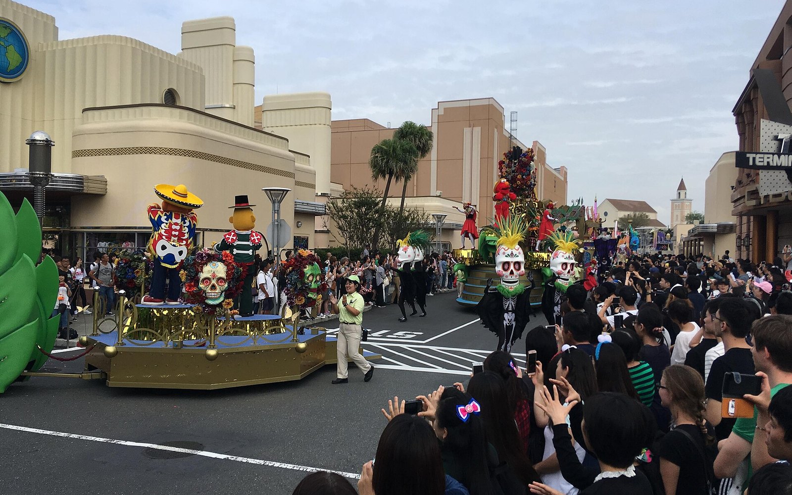Parade floats and stilt-walkers on a New York street set, with a crowd two deep along the curb